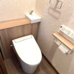 福岡市南区でトイレのリフォームをした施工後の画像。LIXILのJフィットのライトオークのトイレに交換した。便器の後ろがキャビネットになっている。トイレう用品やトイレットペーパーを収納できるようになった。