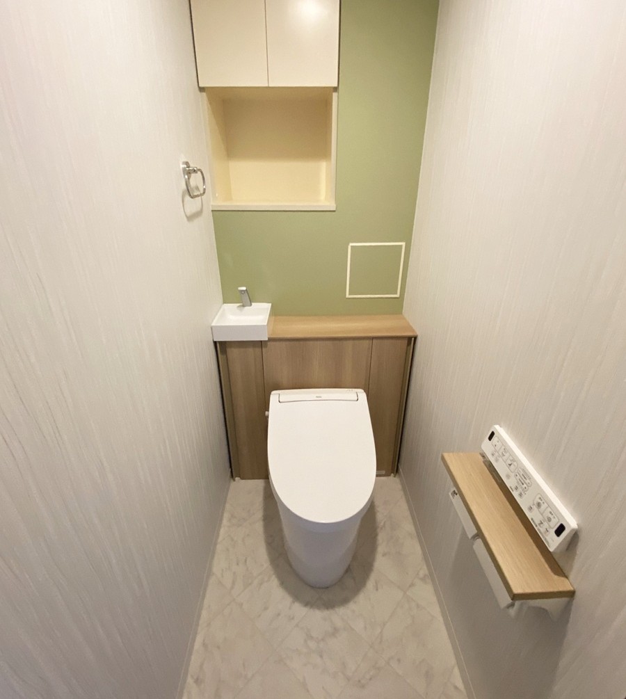 福岡市西区でトイレをリフォームした施工後の画像。新しいトイレはLIXILのJﾌｨｯﾄです。木目調のキャビンネット収納と淡い黄緑色のクロスが相まって自然な感じで落ち着いけれるトイレ空間です。