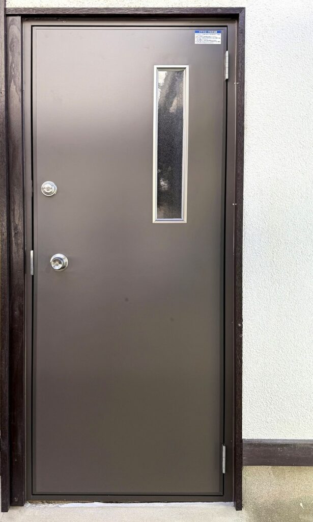 福岡市中央区で勝手口のドアをガラス面が少なく、鍵ロックが２箇所ついている玄関ドアに変更した施工後の画像です。