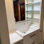 福岡市南区で洗面化粧台をリフォームした施工後の画像。LIXILEVの大和オリジナル洗面化粧台。色は白。洗面化粧台の隣には15㎝幅の同シリーズのトールタイプの収納棚を設置。三面鏡裏とトール収納で収納力がアップしました。アイロンをかけれる台も設置して便利そうな洗面室です。